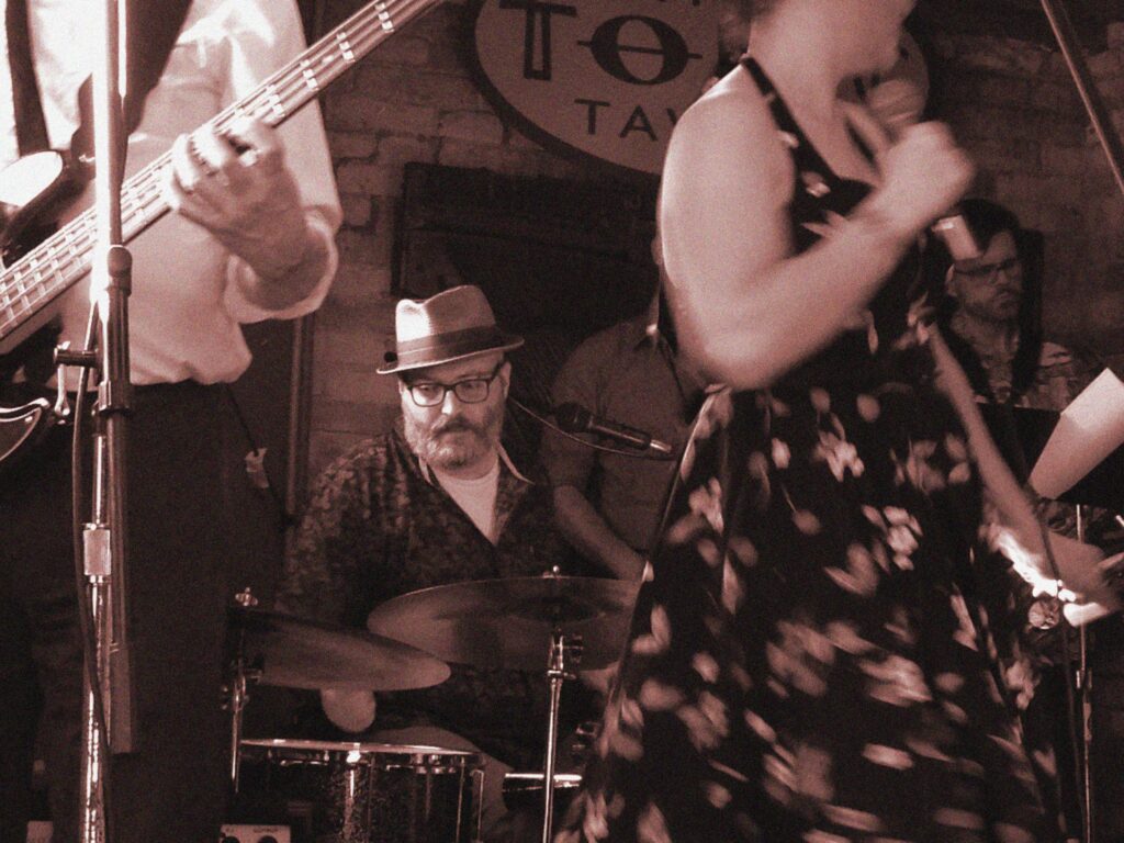 John Carr, leader of the Hungry Williams,  on stage playing the drums.